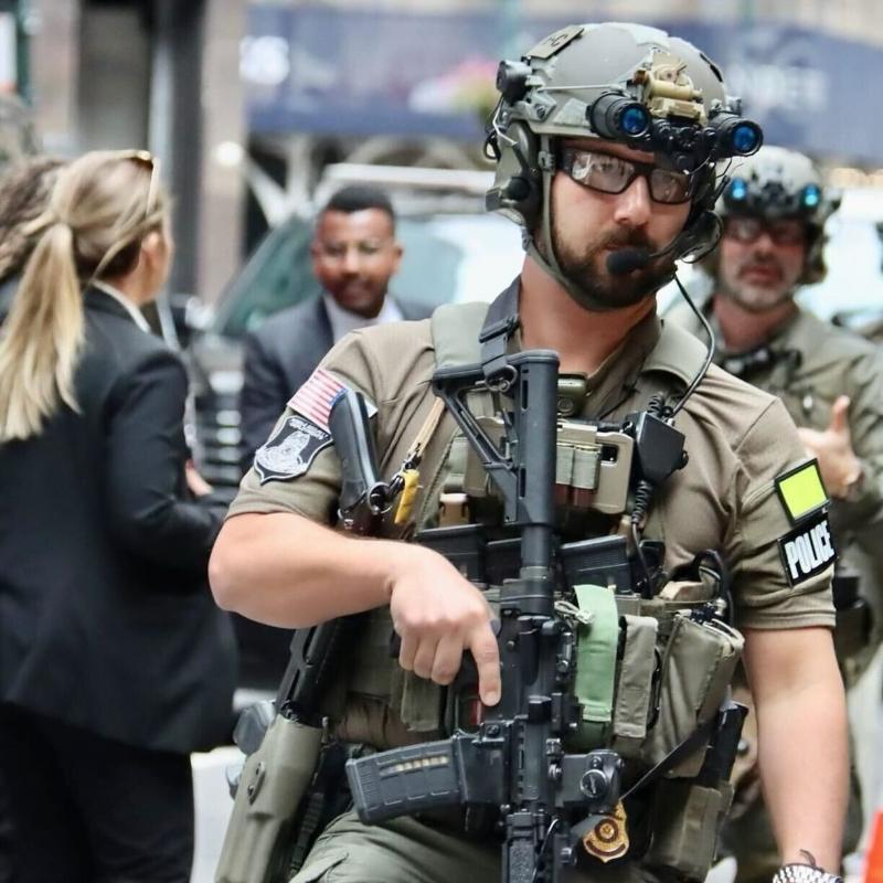 Lifestyle image of the Velocity Systems BOSS Rugby Short Sleeve Combat Shirt worn by law enforcement on duty. USA-made tactical range shirt built from 4-way stretch nylon-spandex for mobility, moisture control, and professional uniform performance.