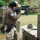 Lifestyle image of the Velocity Systems BOSS Rugby Long Sleeve Combat Shirt worn in a live range training environment, showing its athletic fit, breathable 4-way stretch fabric, and low-profile collar designed for use with plate carriers. This professional-grade tactical base layer is made in the USA and engineered for law enforcement, military, and firearms training- offering moisture wicking, UV protection, and rugged durability for high-intensity field operations.