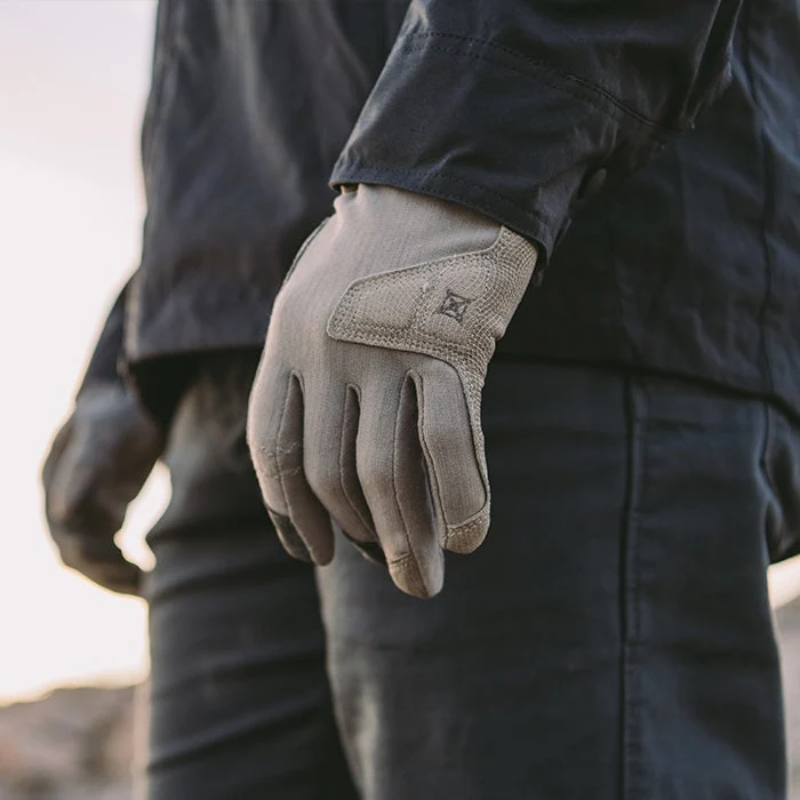 Person wearing a dark jacket and gray gloves with a blurred background
