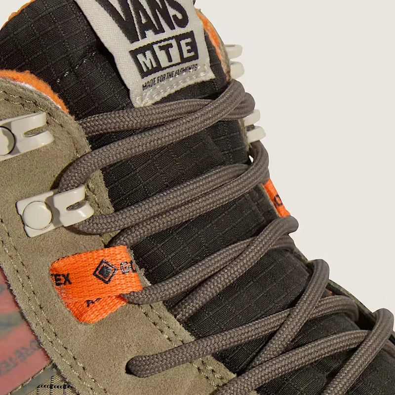 Close-up of a Vans sneaker with brown laces and orange accents on a white background