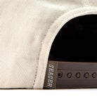 Close-up of a beige cap with a Seager logo on the brim.