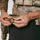 Person adjusting a belt buckle with tactical gear in the background