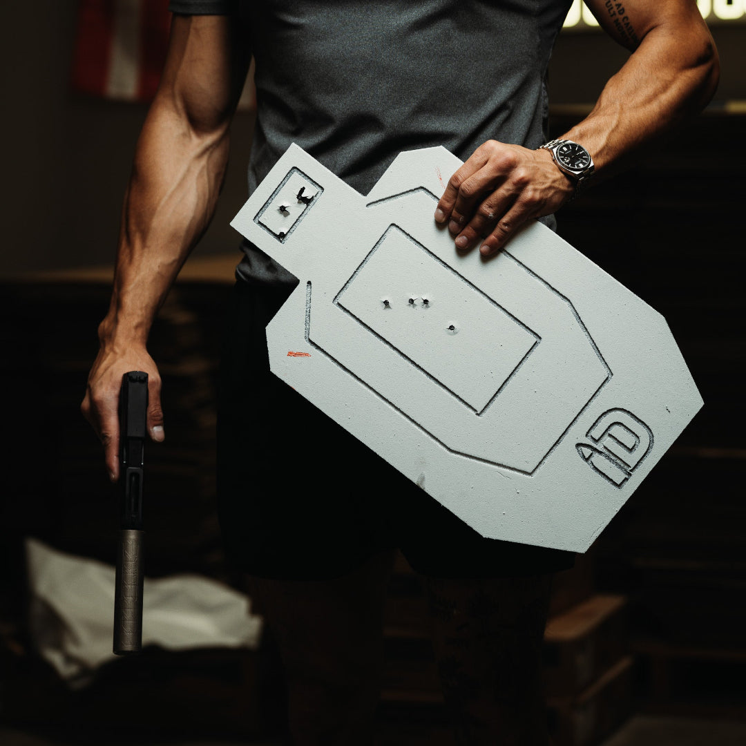 Person holding a white target board with black markings in a dark setting