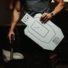 Person holding a white target board with black markings in a dark setting
