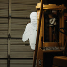 White cutout of a person hiding behind a forklift in a warehouse setting