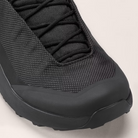 Black sneaker with textured upper and sole on a light gray background