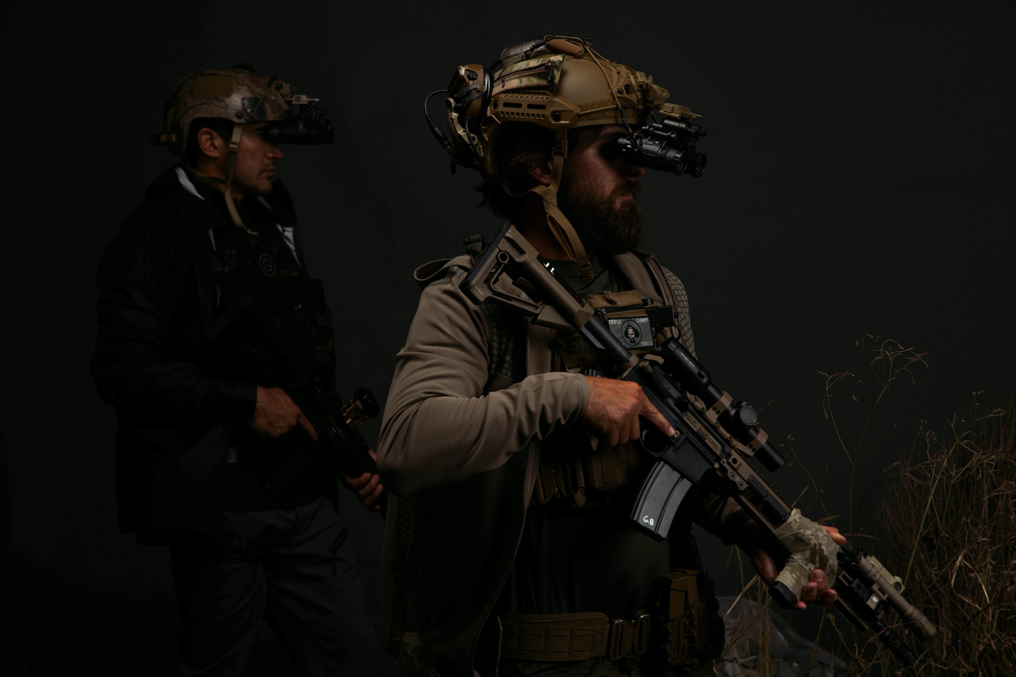 two men wearing tactical gear in the dark