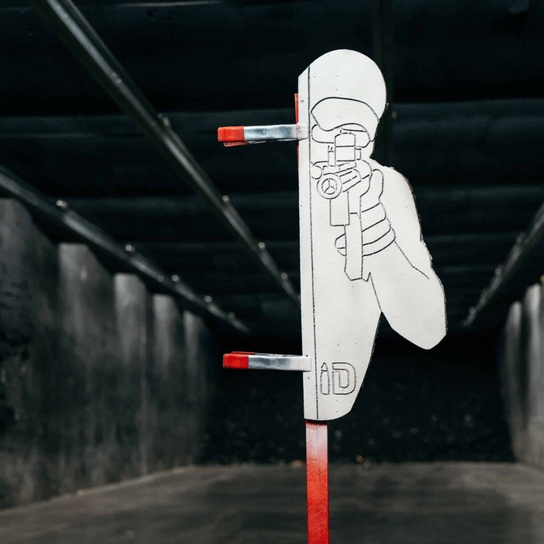 Cardboard cutout of a person holding a gun with a red dot sight against a dark background