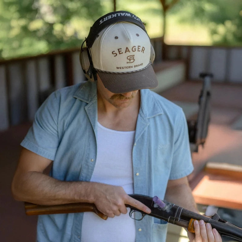 Person holding a rifle on a wooden deck with a blurred background