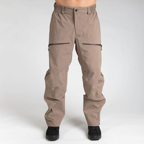 Man wearing hardshell pants in Flat Dark Earth tan color from MTHD Tundra Polartec NeoShell 3L line